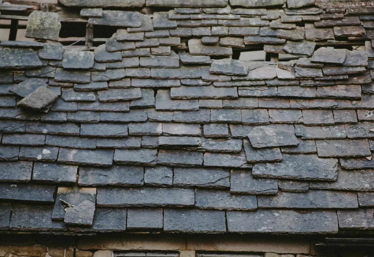 Stone slates slipped, broken and missing, with daylight showing through to the battens